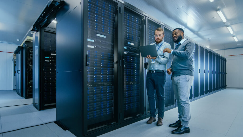 two men standing next to each other in front of servers