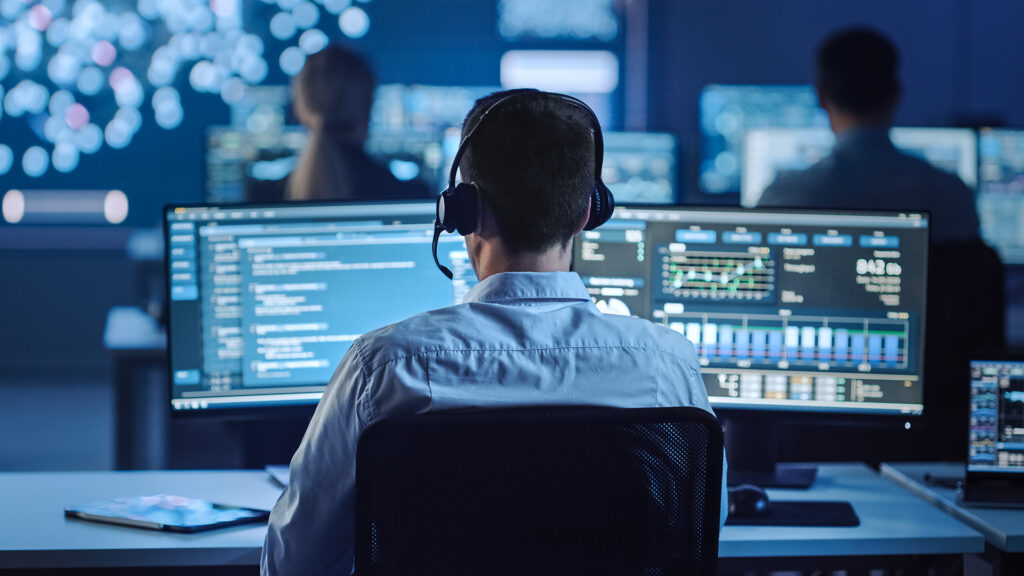 a man sitting in front of two computer monitors