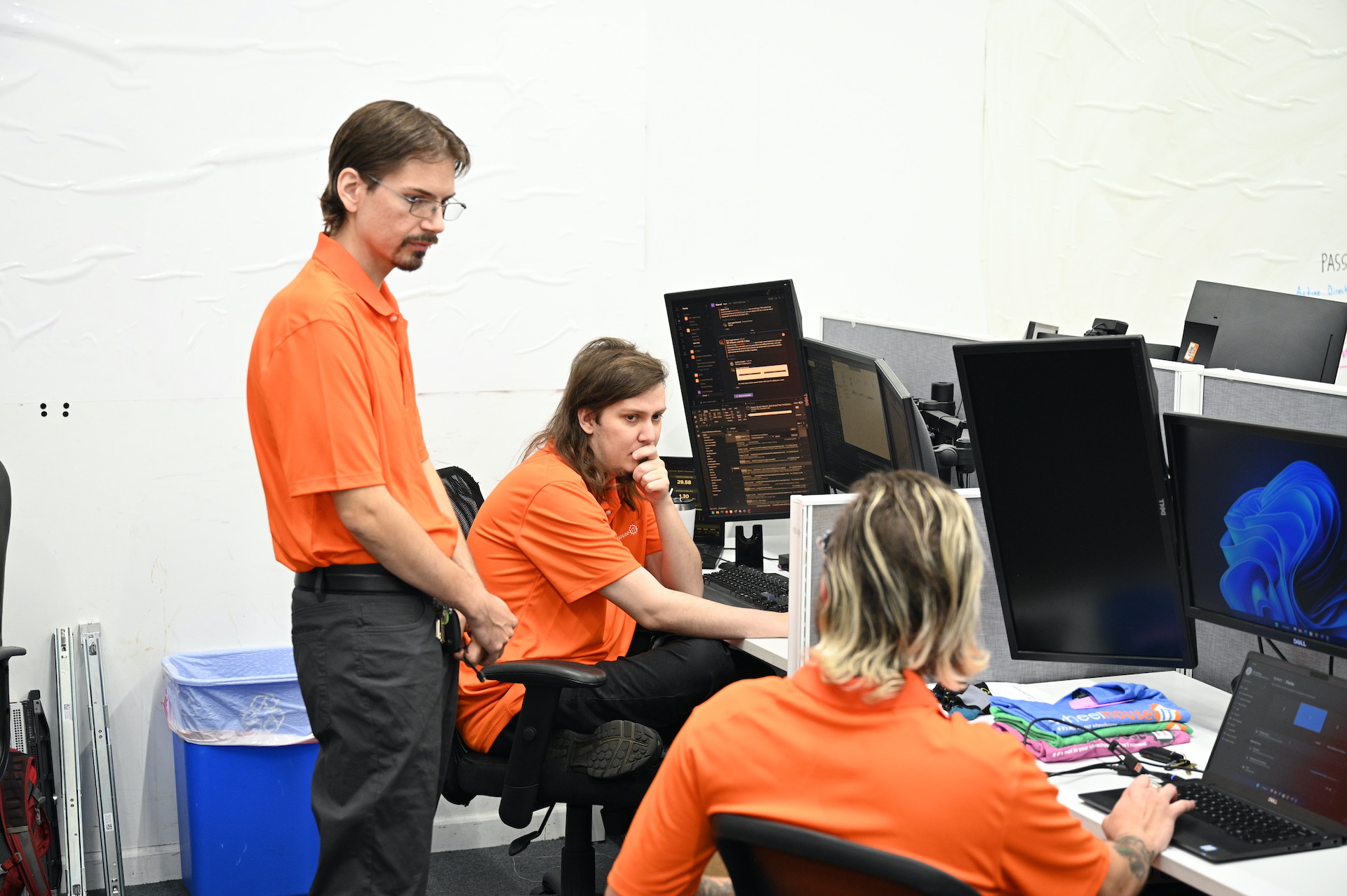 two people in orange shirts working on computers