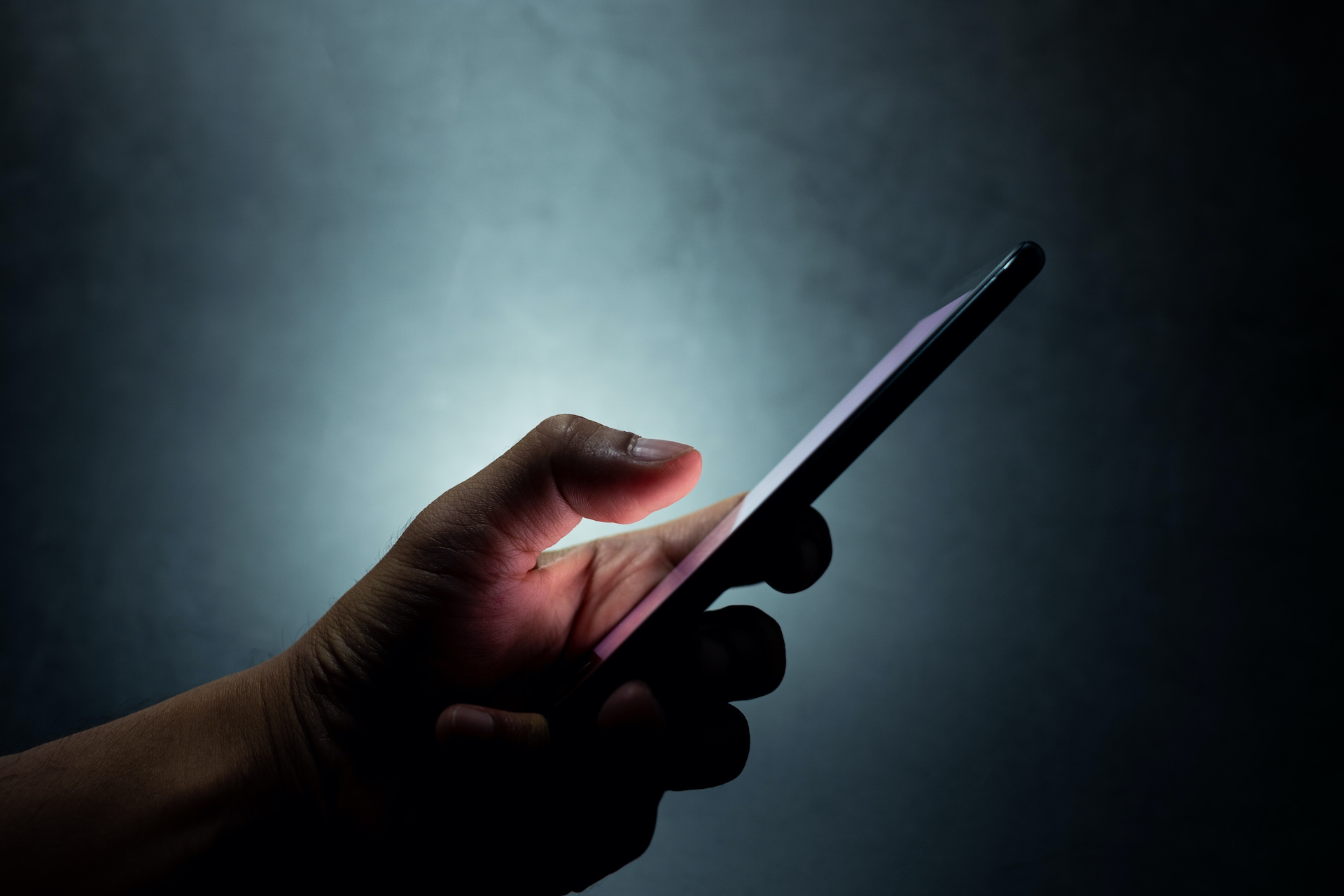 a hand holding a cell phone in the dark