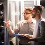 two men looking at servers in a server room talking about legacy hardware
