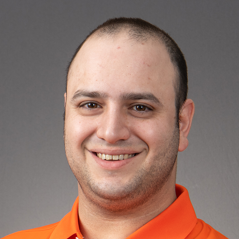 a man in an orange shirt smiling for the camera