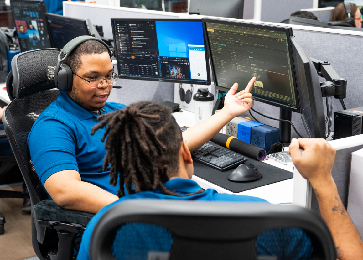 two people sitting at a desk with computers