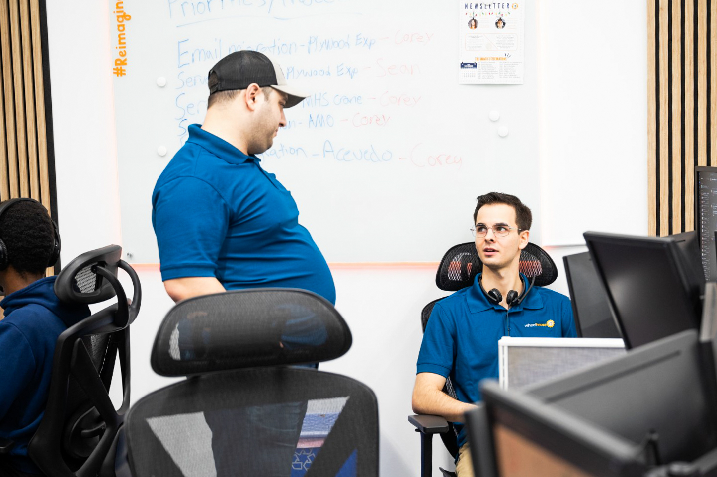 two men in blue shirts are working on computers