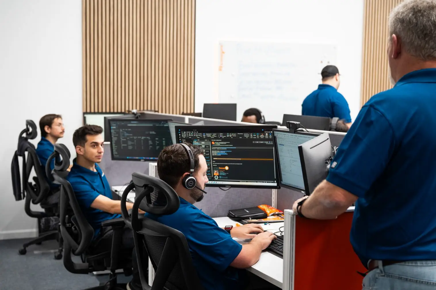 a group of men sitting at desk with headphones on
