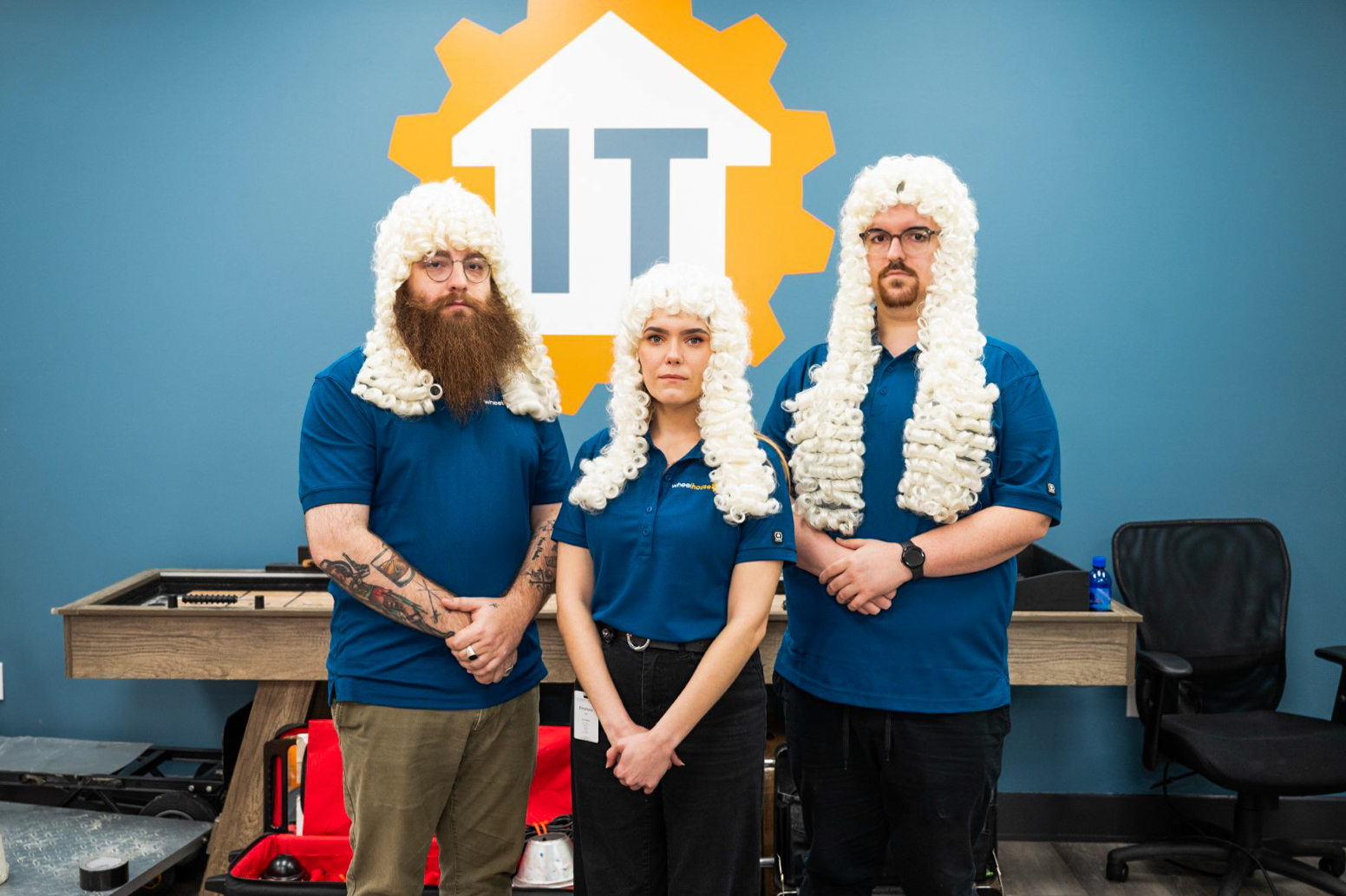 three people wearing wigs and beards in front of a blue wall