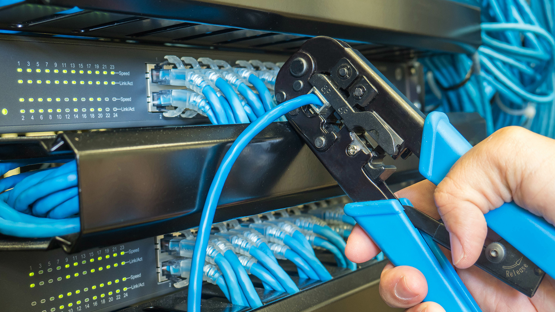 a hand holding a blue cable connected to a server