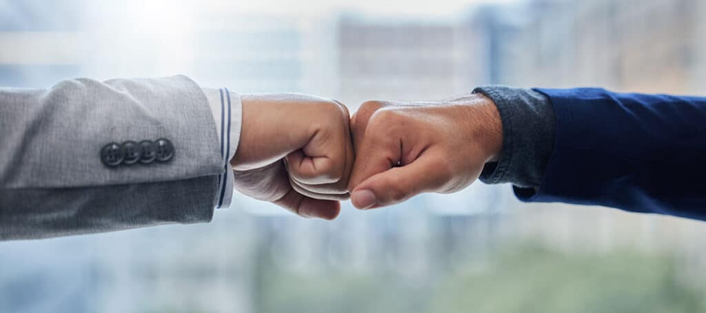 business professionals celebrate a successful msp partnership with a fist bump.