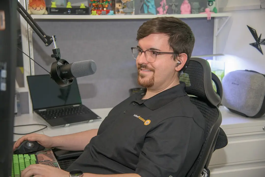 man in professional gaming setup with desktop computer, microphone, collectibles, and aquarium.