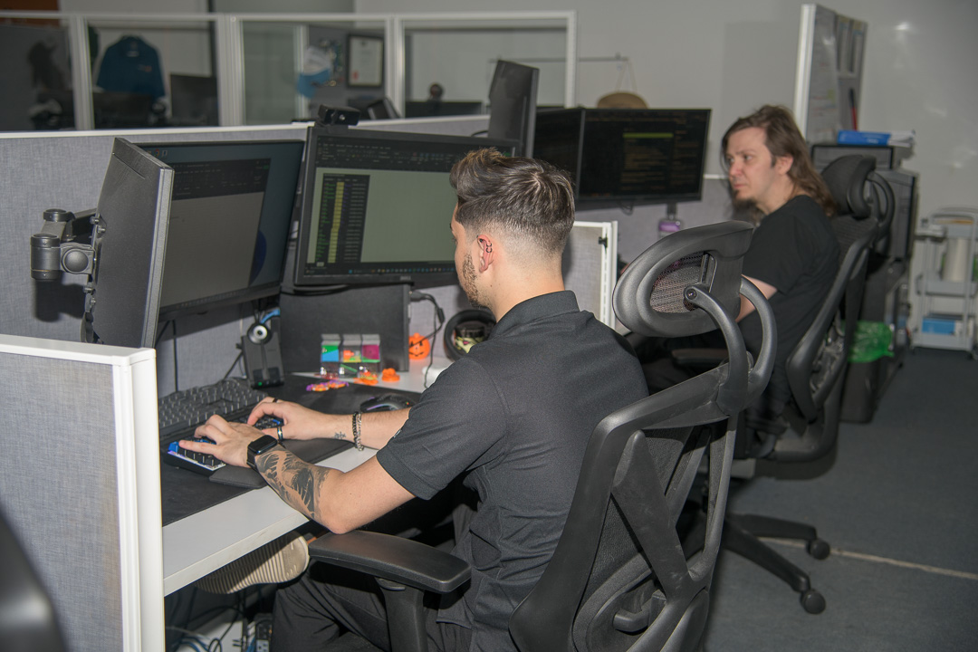 tech-focused individuals in modern office space working on dual monitors, promoting productivity and collaboration.