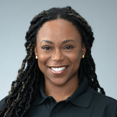 confident woman with dreadlocks in black polo shirt exudes approachable professionalism with a smile.
