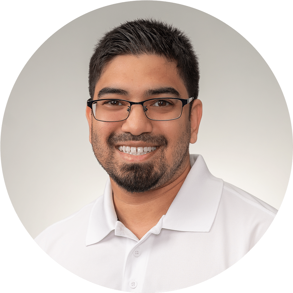 friendly young man in white polo shirt with neat beard and glasses, smiling confidently.