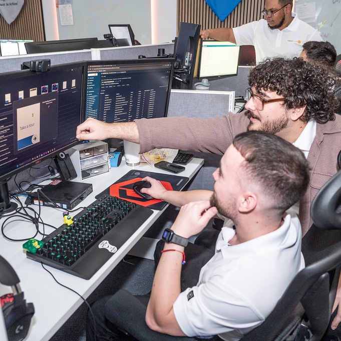 tech team collaboration in modern office workspace with dual monitors and focused individuals.