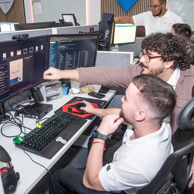 tech team collaboration in modern office workspace with dual monitors and focused individuals.