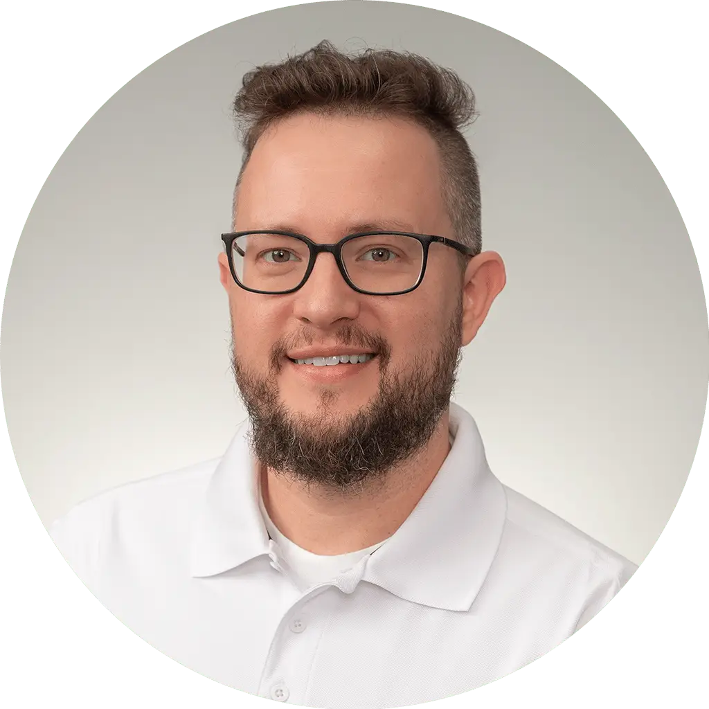 professional headshot of a friendly man in white polo shirt with glasses and beard.
