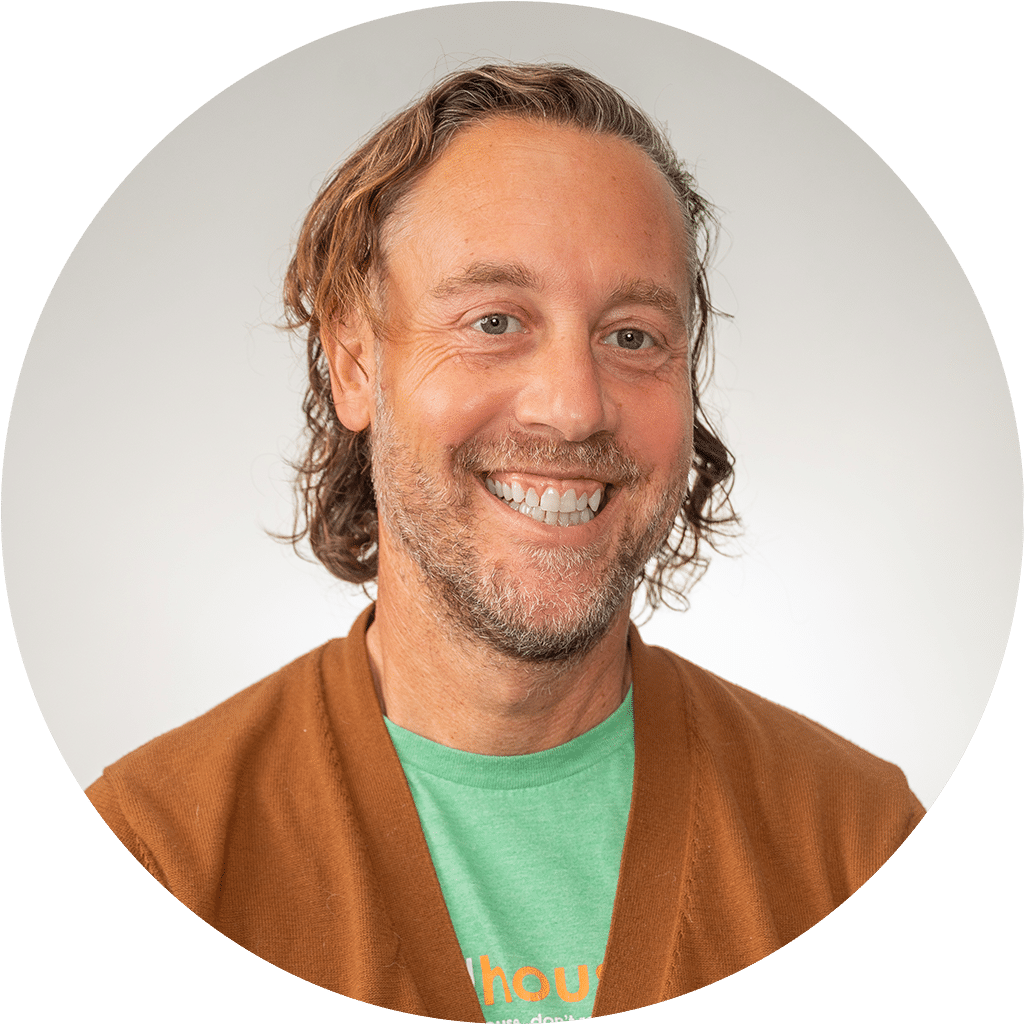 smiling man in cardigan radiating friendliness and approachability.