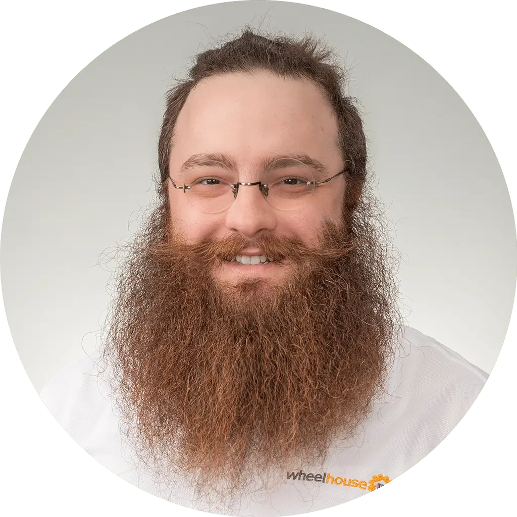 man with vibrant beard in wheelhouse it shirt exuding professionalism and approachability.