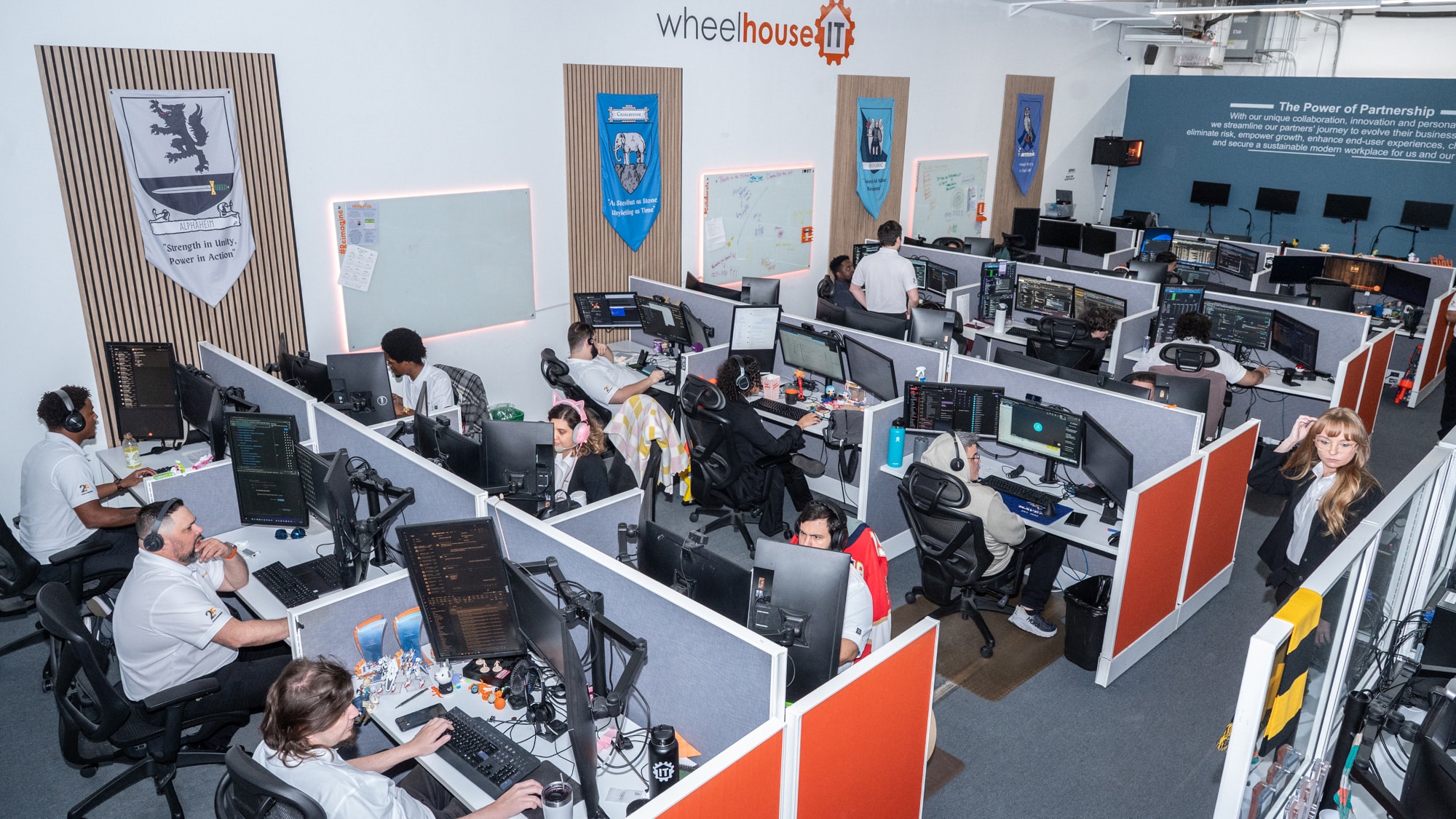 modern office workspace for tech company with dual monitors, teamwork banners, and whiteboard notes.