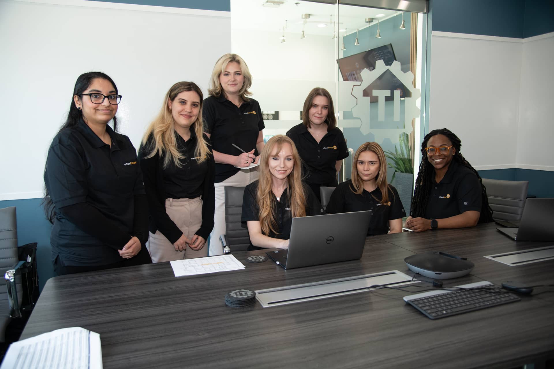 professional team meeting in modern office with women dressed in black polo shirts.