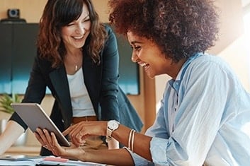 two professional women collaborating on a project in a modern office setting.