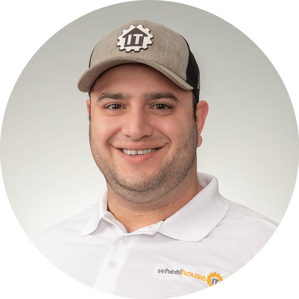 professional man in it industry wearing branded attire, smiling confidently in light-filled setting.