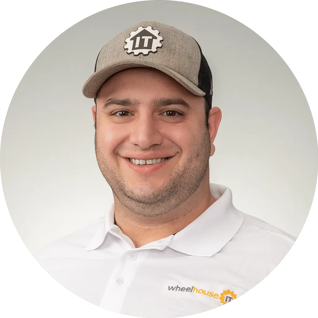 professional man in it industry wearing branded attire, smiling confidently in light-filled setting.