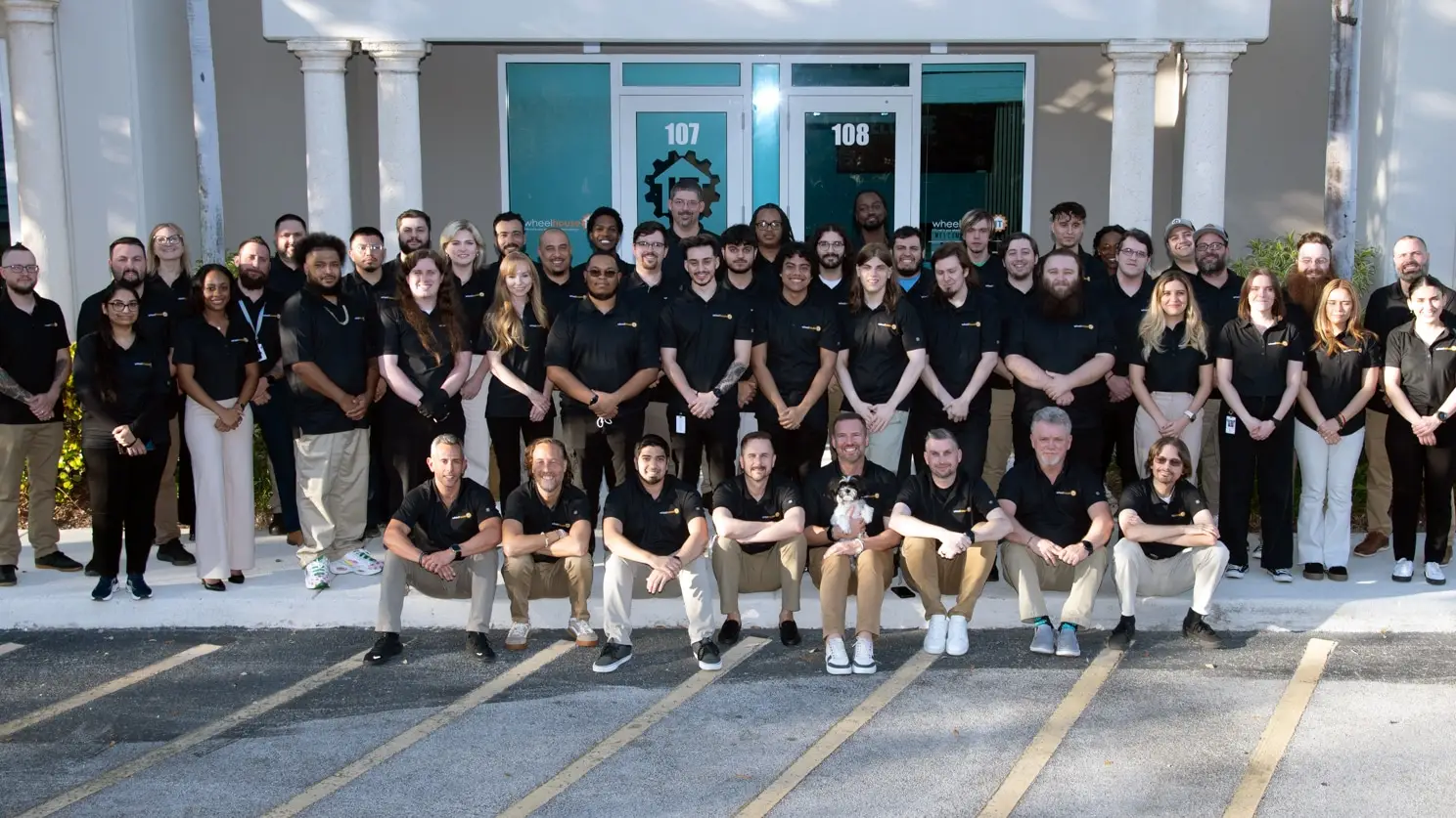 diverse group celebrating outside modern workplace building in team photo.