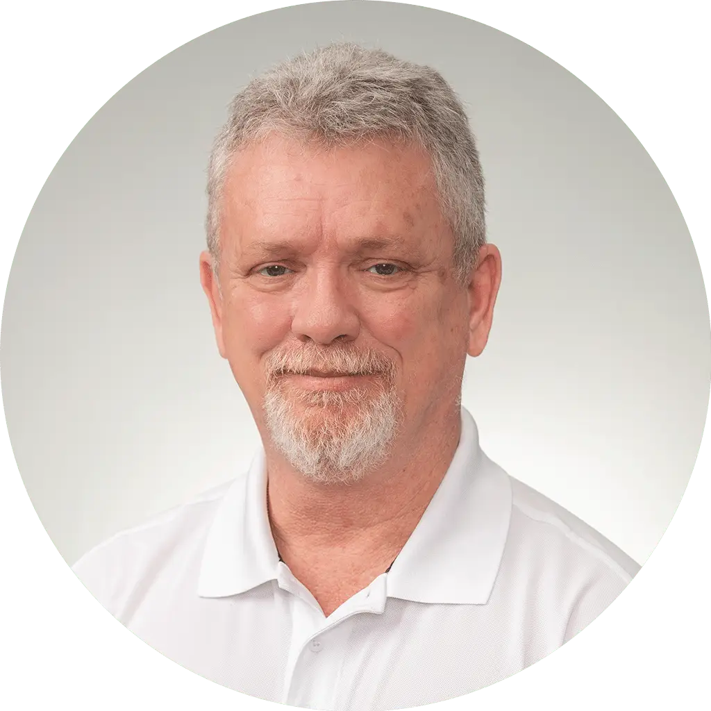 middle-aged man with gray hair and white polo shirt against a serene gray background.