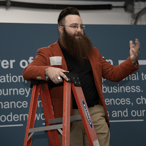 confident professional speaker on ladder discussing business connections at workshop.