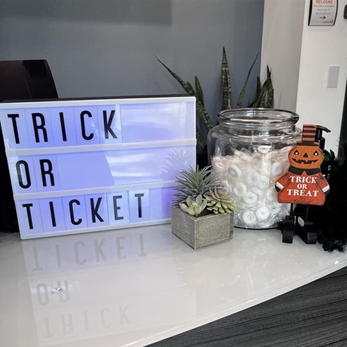whimsical halloween display with trick or treat sign, candy jar, and festive pumpkin figure.