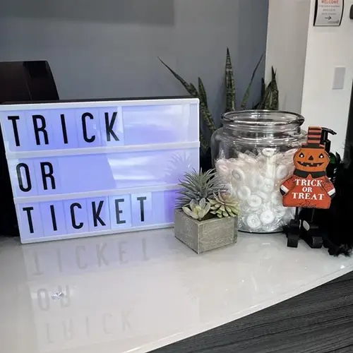 whimsical halloween display with trick or treat sign, candy jar, and festive pumpkin figure.