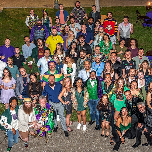 lively diverse group at festive outdoor celebration with vibrant attire and colorful decorations.