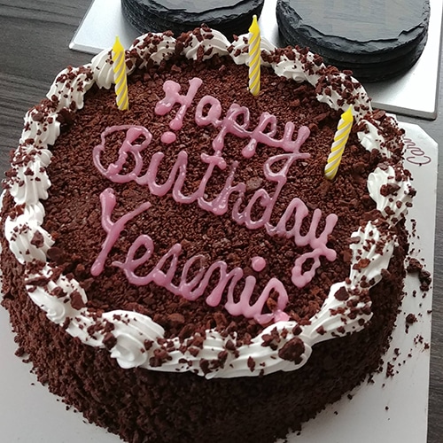 beautifully decorated birthday cake with rich red chocolate crumbs, white whipped cream, and candles.