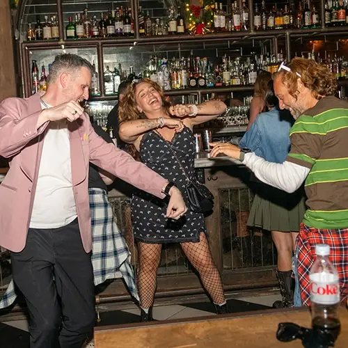 vibrant group enjoying lively night at bar with dancing, music, and joyful atmosphere.