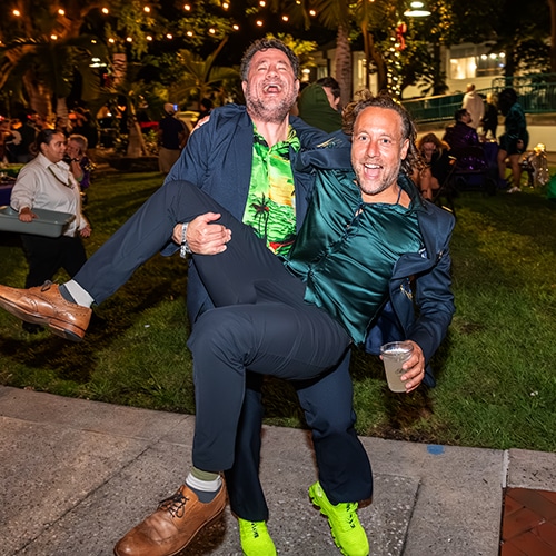 two friends enjoying a festive outdoor celebration under string lights.