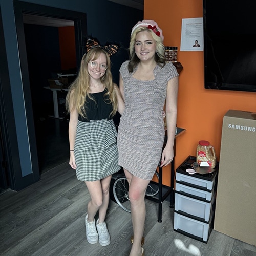 two friends in stylish outfits posing in a modern indoor setting.