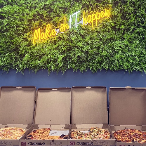 vibrant pizza dining scene with neon sign and green wall.