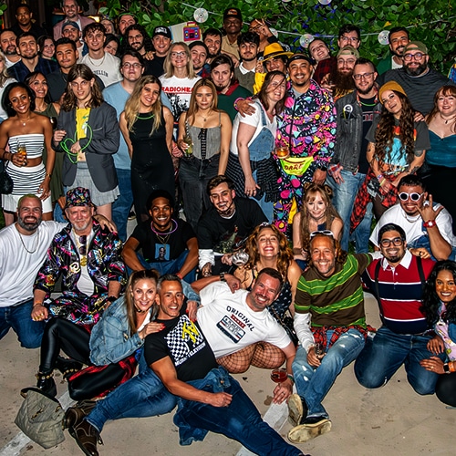 gathering of diverse group at vibrant outdoor celebration with greenery and festive attire.