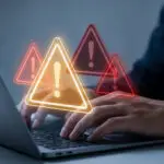 Person typing on laptop with glowing biggest security risk alerts.