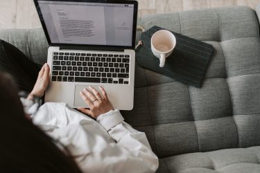 a person sitting on a couch using a laptop computer