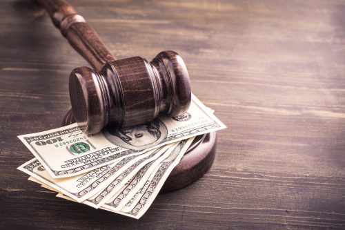 a wooden judge's hammer on top of money