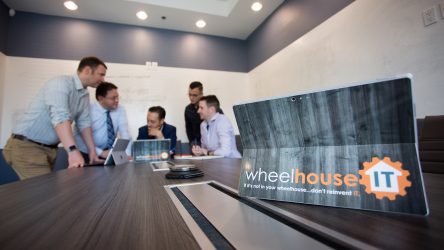 a group of people sitting around a table with laptops