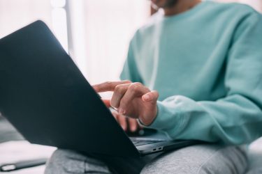 a man sitting on a bed using a laptop computer