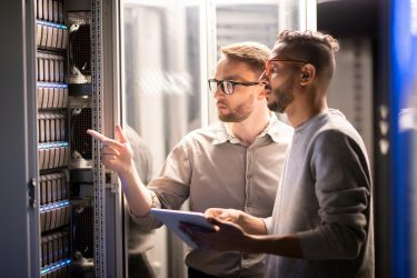 two men looking at servers in a server room talking about legacy hardware